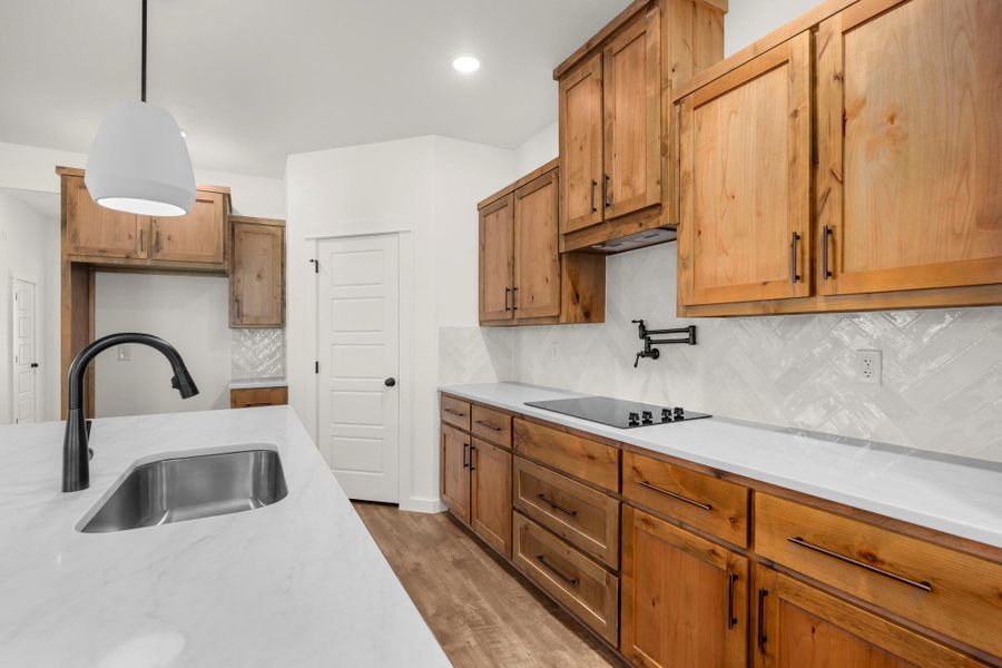 A contemporary kitchen showcasing natural wood cabinetry and sleek, white countertops with a subway tile backsplash.