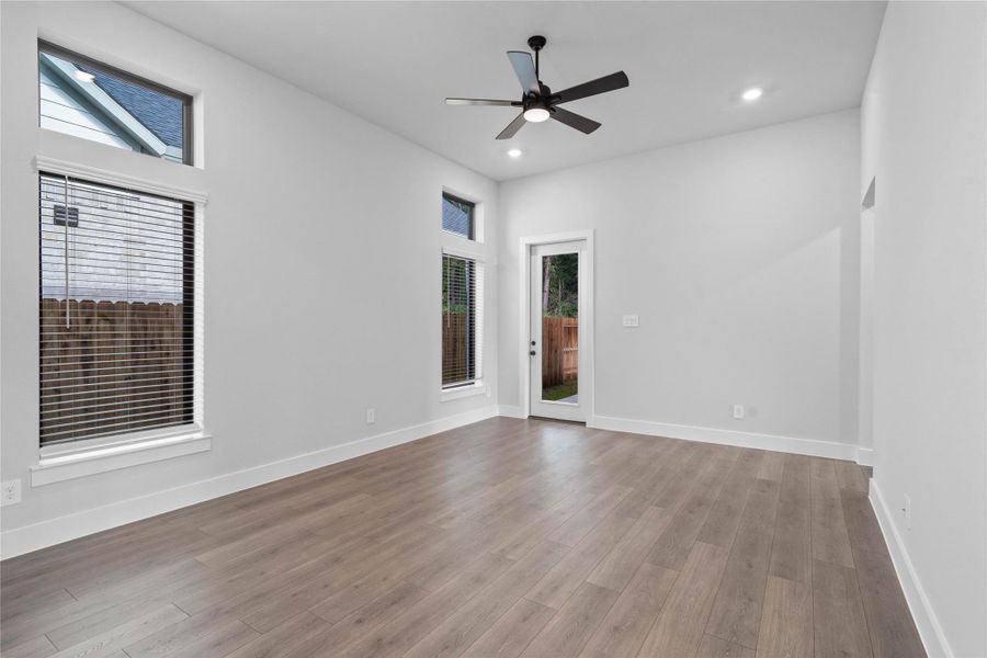 A bright and airy open-concept space featuring tile flooring, high ceilings with recessed lighting and ceiling fan, abundant natural light from large windows (fitted with blinds), and an access door to the back covered patio. A bright and airy open-concept space featuring tile flooring, high ceilings with recessed lighting and ceiling fan, abundant natural light from large windows (fitted with blinds), and an access door to the back covered patio.