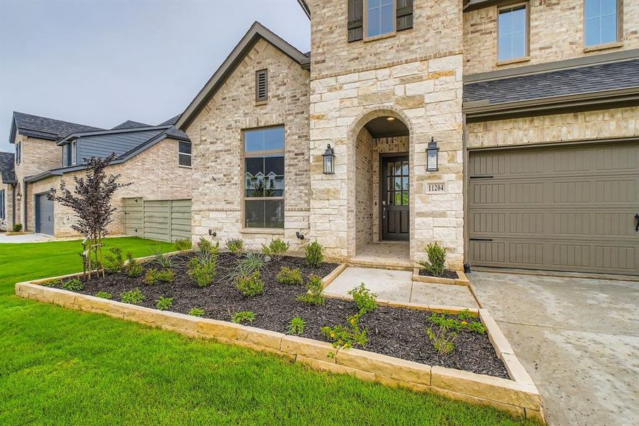 View of front of property with a front yard, stone siding, concrete driveway, and a garage View of front of property with a front yard, stone siding, concrete driveway, and a garage