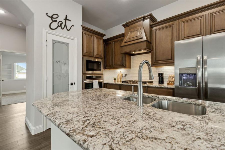 Kitchen includes granite countertops, white subway tile and a glass custom pantry door.