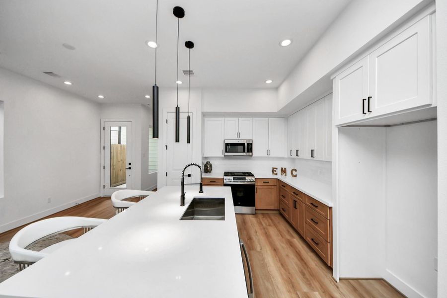 Discover a sleek, modern kitchen featuring gleaming stainless steel appliances, elegant white cabinetry, and a spacious island perfect for entertaining.