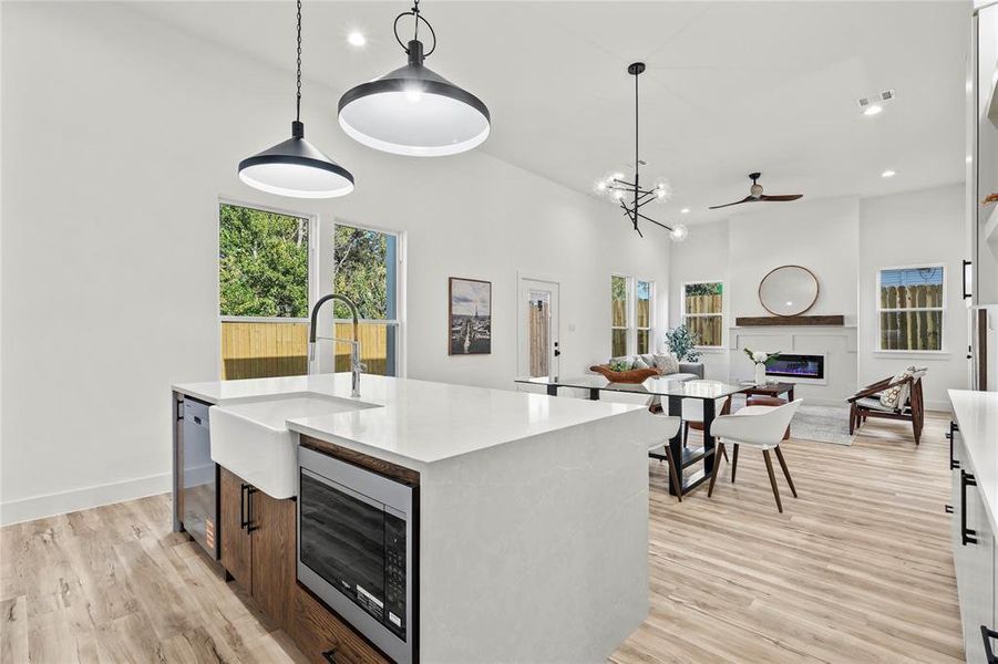 Kitchen with decorative light fixtures, stainless steel microwave, light stone counters, healthy amount of natural light, and recessed lighting