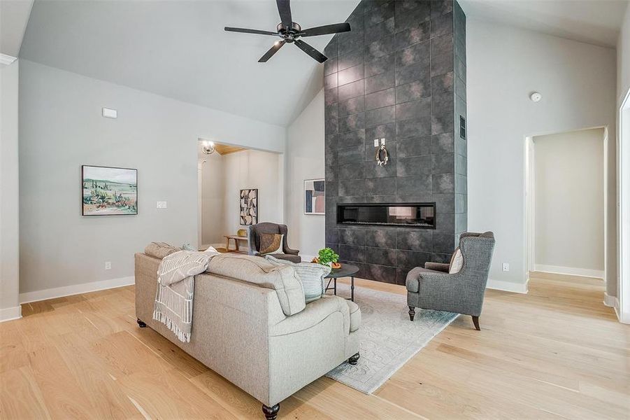 Living room with high vaulted ceiling, a ceiling fan, and light wood finished floors Living room with high vaulted ceiling, a ceiling fan, and light wood finished floors