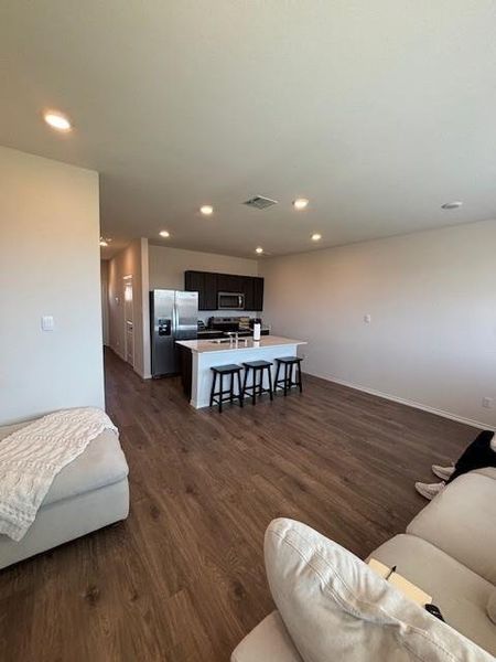 Open-concept living area featuring wood-finish flooring, recessed lighting, and a kitchen island with seating