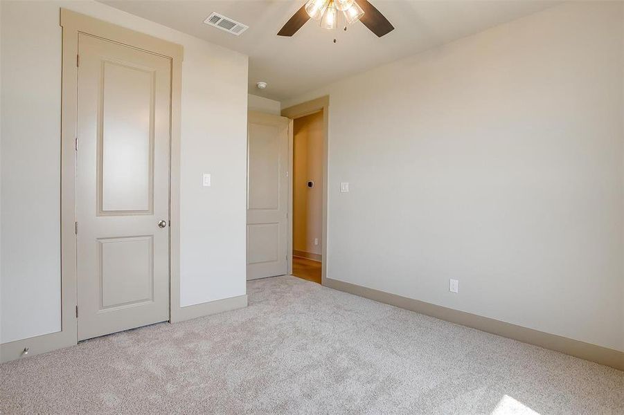 Unfurnished bedroom featuring carpet flooring, visible vents, ceiling fan, and baseboards