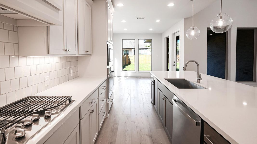 Kitchen featuring appliances with stainless steel finishes, light wood-style floors, decorative light fixtures, recessed lighting, and custom range hood Kitchen featuring appliances with stainless steel finishes, light wood-style floors, decorative light fixtures, recessed lighting, and custom range hood