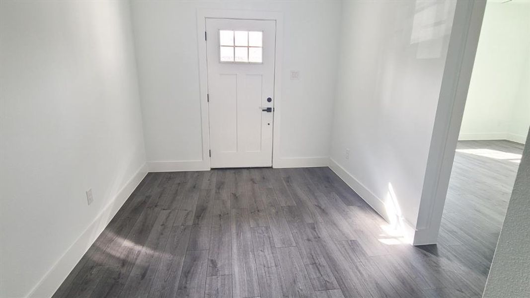 Entryway featuring wood-finish flooring, white baseboards, and a white paneled door with frosted glass inserts Entryway featuring wood-finish flooring, white baseboards, and a white paneled door with frosted glass inserts