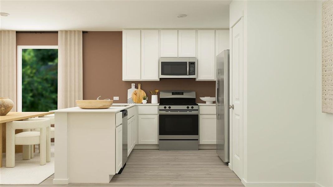 Kitchen featuring light wood finished floors, appliances with stainless steel finishes, a peninsula, light countertops, and white cabinetry