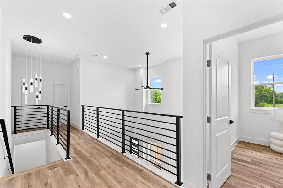 Open loft area featuring wood-finish flooring and contemporary black metal railings