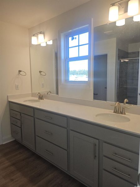 Full bathroom with double vanity, a stall shower, and water closet