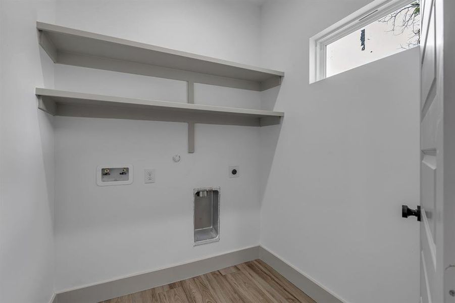 Washroom featuring light wood-type flooring, washer hookup, electric dryer hookup, and hookup for a gas dryer Washroom featuring light wood-type flooring, washer hookup, electric dryer hookup, and hookup for a gas dryer
