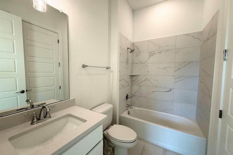 A well-appointed bathroom with marble-inspired tile, offering a sleek vanity and tub for relaxation. A well-appointed bathroom with marble-inspired tile, offering a sleek vanity and tub for relaxation.