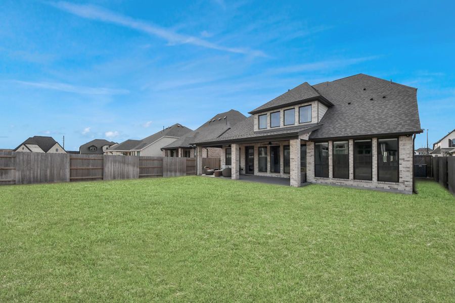 Backyard perspective showcasing covered patio and rear elevation.