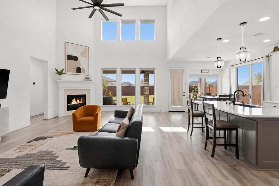 Warm and inviting, this stunning living space features a cozy fireplace with modern tile surround, creating the perfect ambiance for relaxation. The natural light floods the room, while the open layout seamlessly connects to the kitchen.