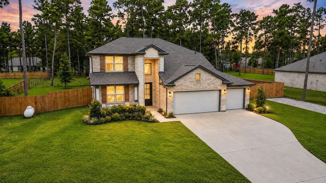 Stunning two-story home with a spacious driveway and three-car garage, nestled amidst lush greenery and mature trees, offering privacy and tranquility.
