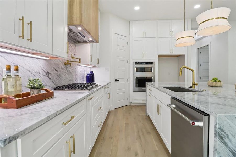 Kitchen featuring appliances with stainless steel finishes, recessed lighting, white cabinetry, light wood-type flooring, and light stone countertops