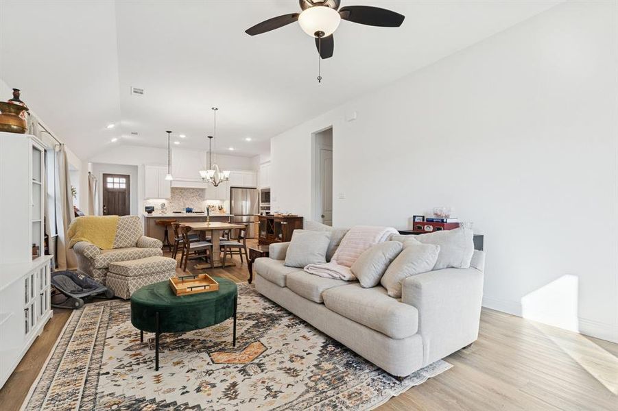 Living room featuring a chandelier, lofted ceiling, light wood-type flooring, recessed lighting, and ceiling fan Living room featuring a chandelier, lofted ceiling, light wood-type flooring, recessed lighting, and ceiling fan