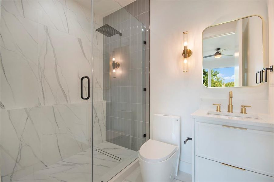 Bathroom featuring vanity, a marble finish shower, and ceiling fan Bathroom featuring vanity, a marble finish shower, and ceiling fan