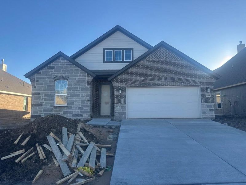 View of front of house featuring stone siding, driveway, and an attached garage