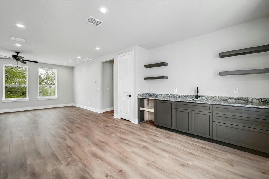 Bar with recessed lighting, visible vents, ceiling fan, light wood-type flooring, and baseboards