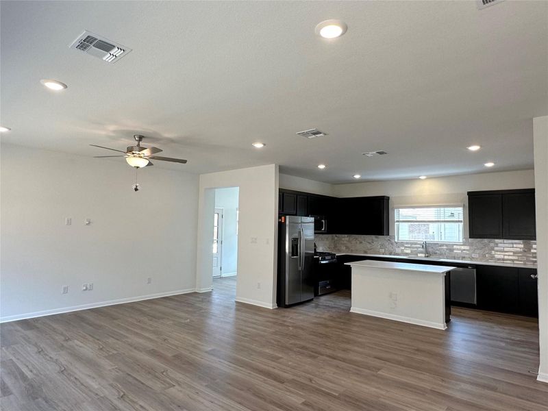 Kitchen featuring dark cabinets, open floor plan, stainless steel appliances, dark wood-style floors, and recessed lighting