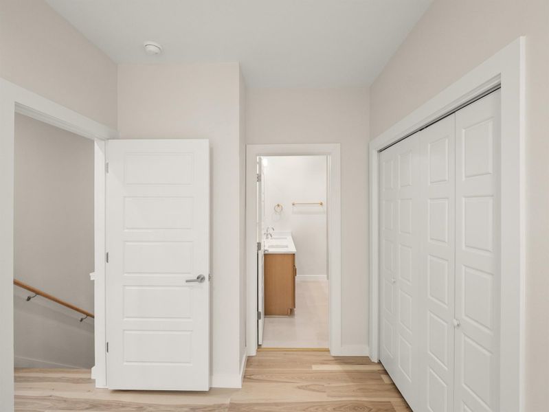Hallway featuring wood-finish flooring, white paneled doors, and a built-in closet with bi-fold doors