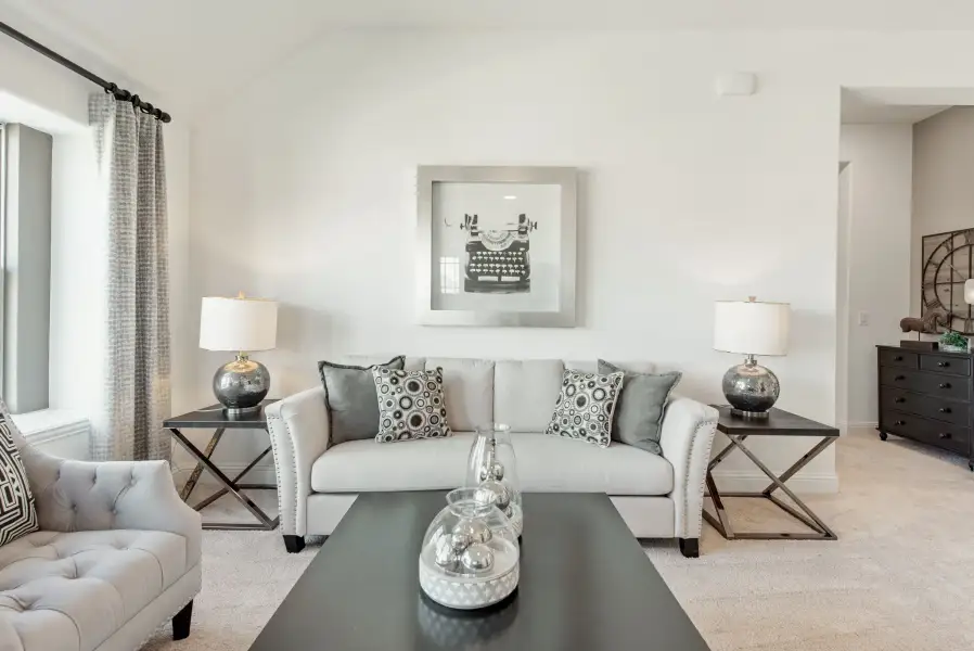 Living room with gray sofa, dark coffee table, two end table lamps, and framed wall art on white walls