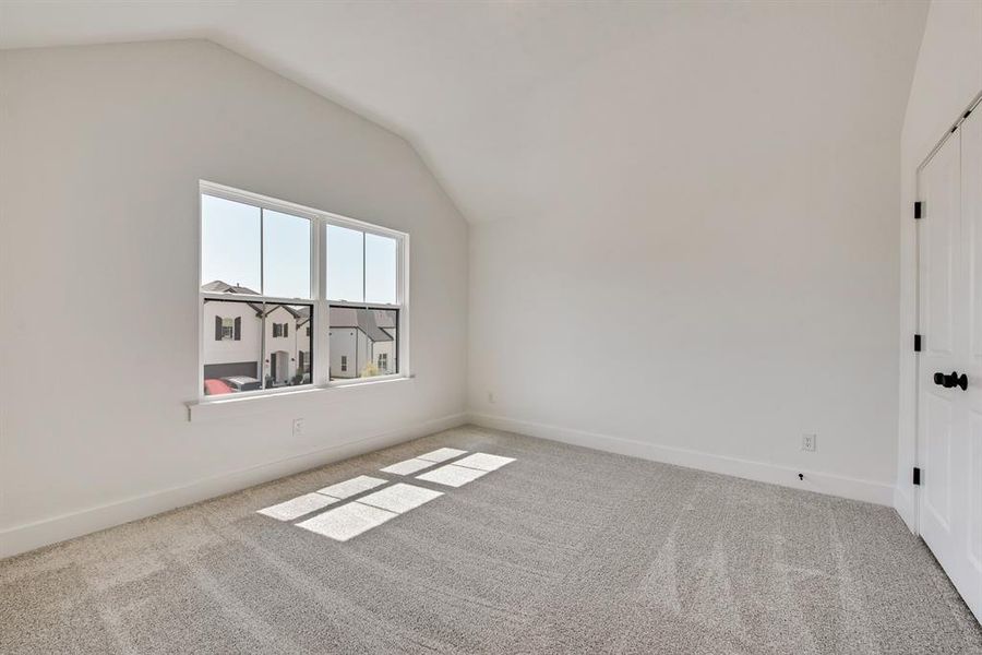 Unfurnished bedroom featuring lofted ceiling and light carpet Unfurnished bedroom featuring lofted ceiling and light carpet