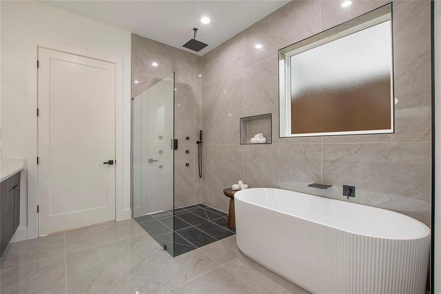 Bathroom featuring walk in shower, tile walls, a freestanding bath, vanity, and marble finish floors Bathroom featuring walk in shower, tile walls, a freestanding bath, vanity, and marble finish floors
