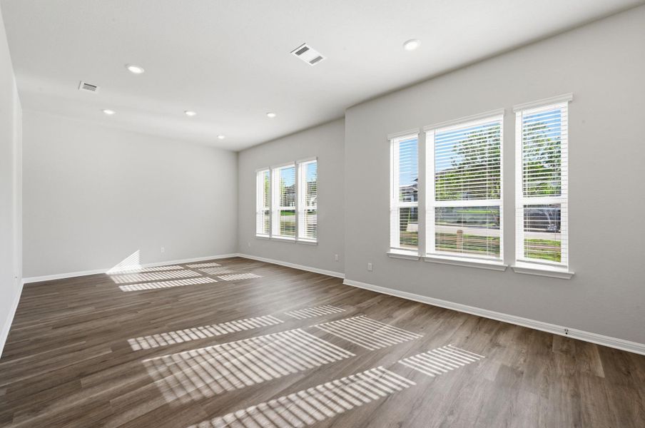 Spacious room featuring wood-finish flooring, recessed lighting, and multiple windows with blinds Spacious room featuring wood-finish flooring, recessed lighting, and multiple windows with blinds