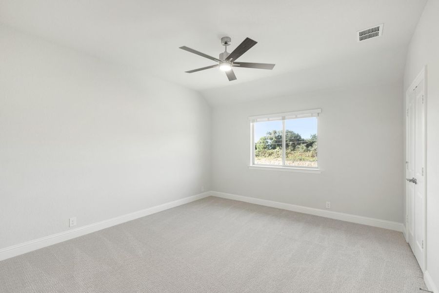 Empty bedroom with vaulted ceiling, ceiling fan, carpet flooring, and a single window