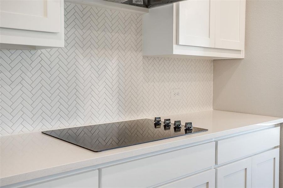 Kitchen featuring white cabinets and black cooktop Kitchen featuring white cabinets and black cooktop