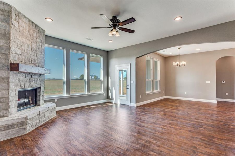 Unfurnished living room with a chandelier, dark wood-style flooring, ceiling fan, a fireplace, and recessed lighting Unfurnished living room with a chandelier, dark wood-style flooring, ceiling fan, a fireplace, and recessed lighting