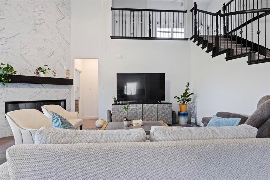 Living room with a high ceiling, a premium fireplace, wood finished floors, and stairway
