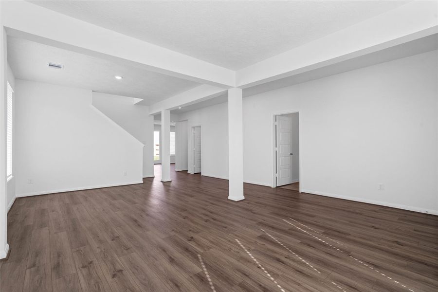 Another perspective view from formal living to formal dining, staircase and entrances into the laundry room/garage entry and powder room.