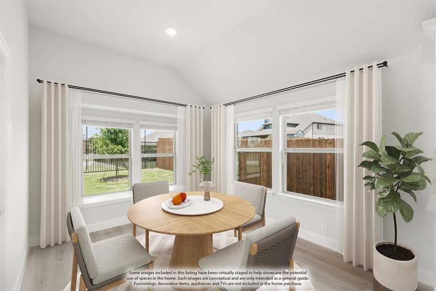 Bright dining nook with round wood table, four chairs, vaulted ceiling, and large windows overlooking backyard Bright dining nook with round wood table, four chairs, vaulted ceiling, and large windows overlooking backyard