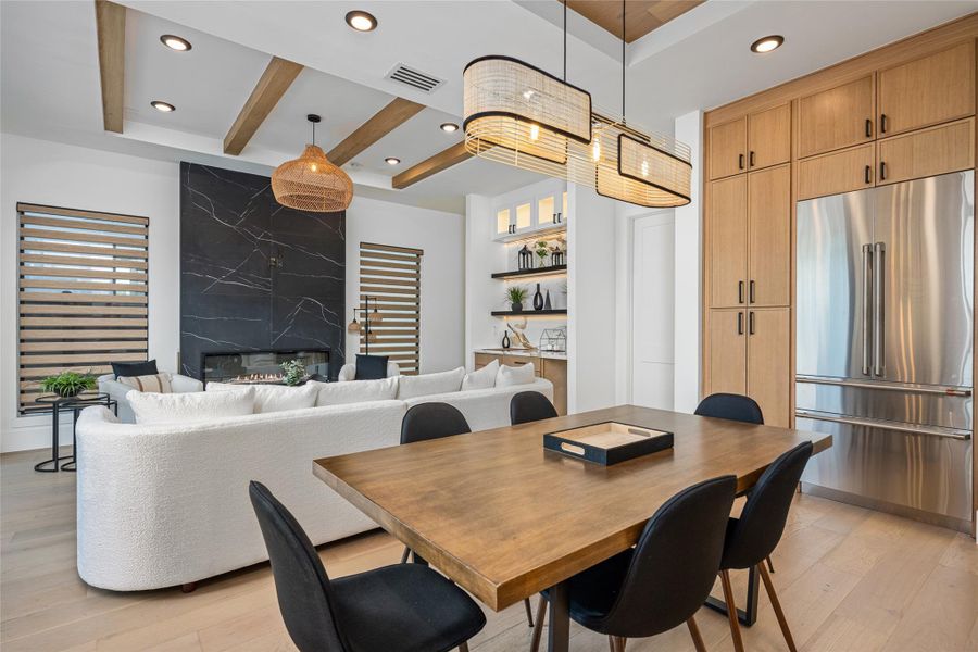 The dining space is both stylish and functional, featuring a designer chandelier and a coffered ceiling accented with rich wood inlays