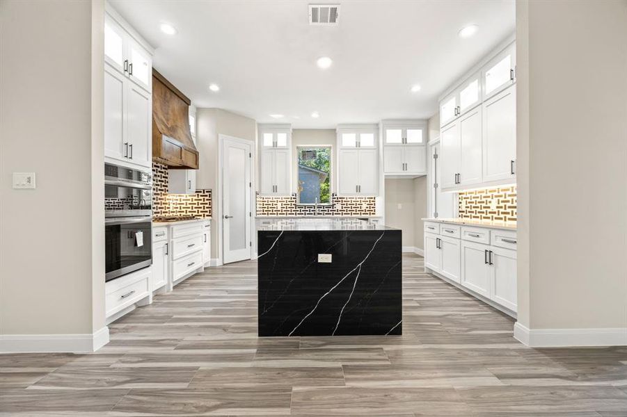 Kitchen with stainless steel  appliances, decorative backsplash, an elegant waterfall island, and white cabinets