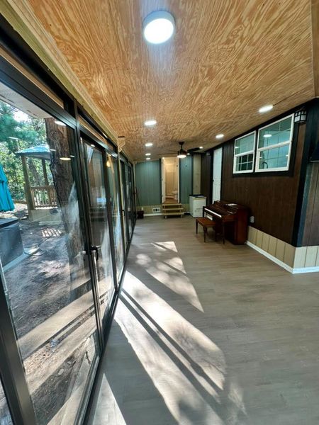 A spacious sunroom with large windows offers serene views of the surrounding natural landscape.