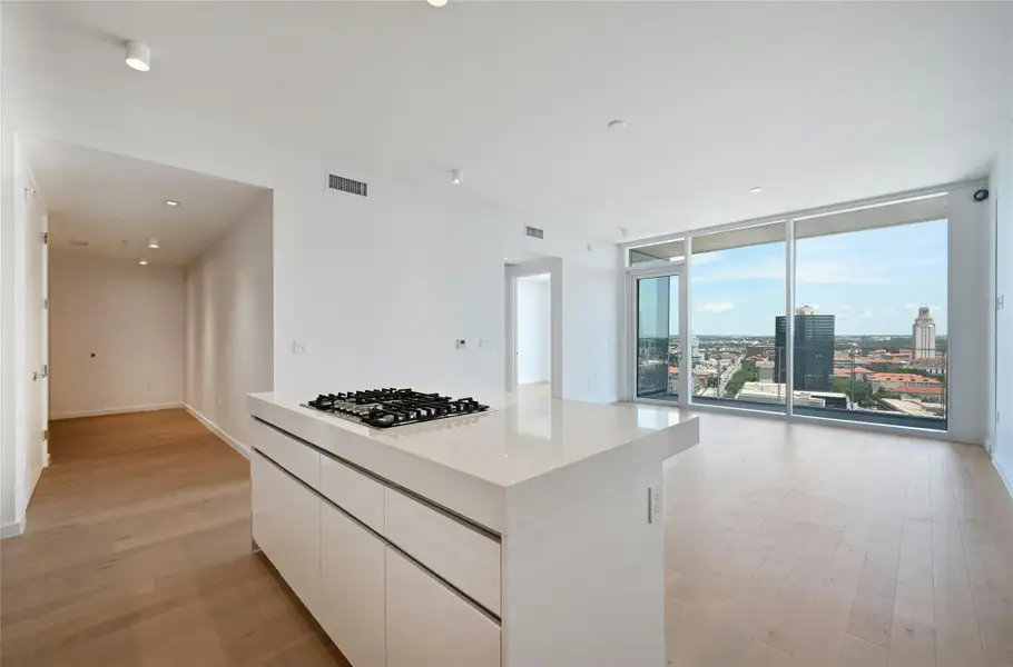 Sophisticated open-concept kitchen featuring sleek Bosch appliances, integrated wood-paneled cabinetry, and a glossy white island ideal for casual dining or entertaining—all seamlessly connected to the main living space with clean, modern lines.