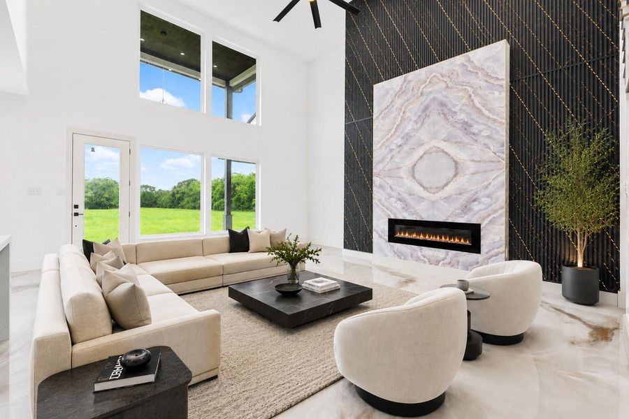 *Virtually Staged*Dramatic two-story living room showcasing a floor-to-ceiling designer fireplace feature wall, luxury marble-style flooring, and abundant natural light throughout.