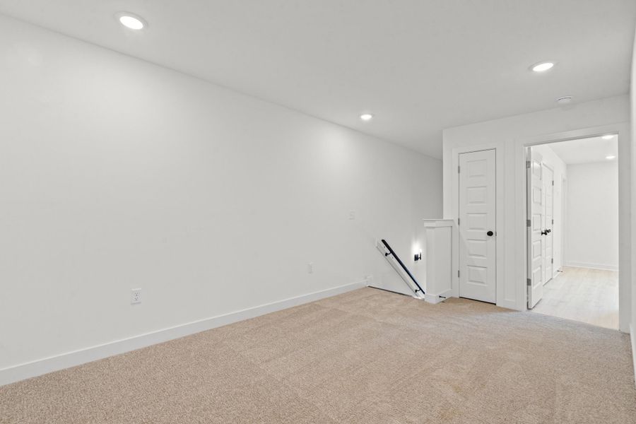 Neutral-toned carpeting, recessed ceiling lighting, and crisp white walls