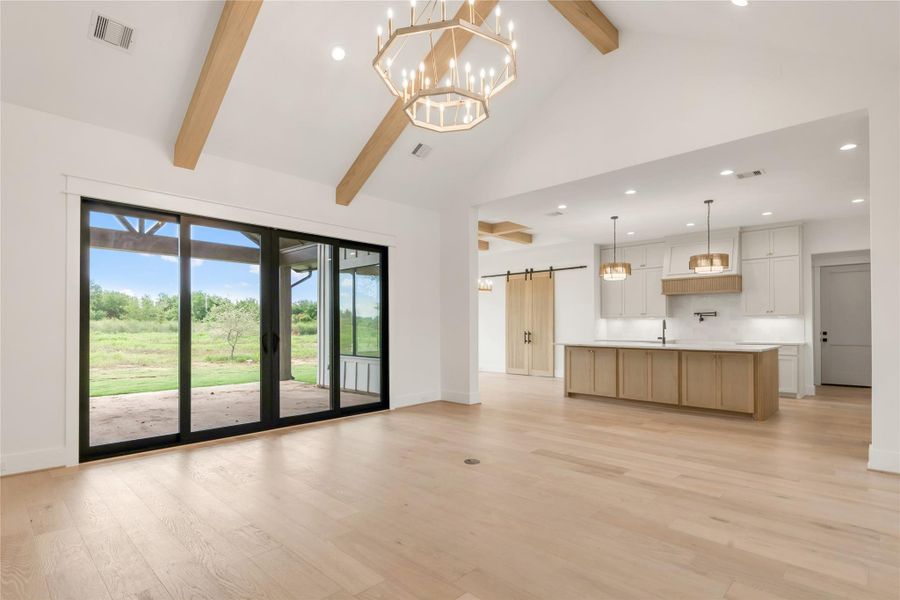 Unfurnished living room featuring a barn door, hanging lights, and light wood-type flooring