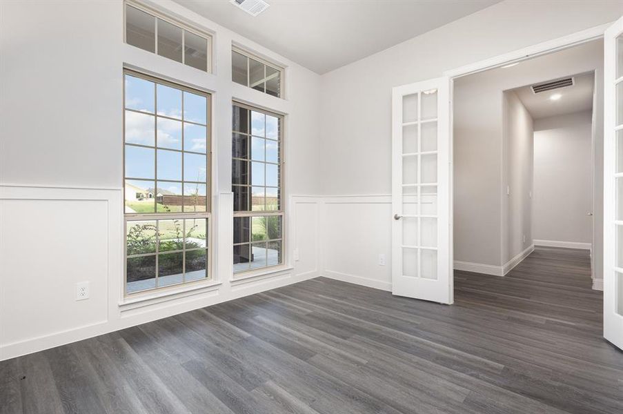 Empty room with dark wood finished floors, french doors, and wainscoting Empty room with dark wood finished floors, french doors, and wainscoting