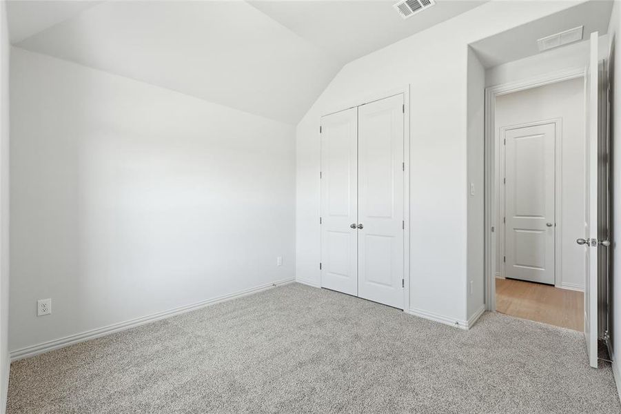 Unfurnished bedroom featuring carpet floors, a closet, and vaulted ceiling