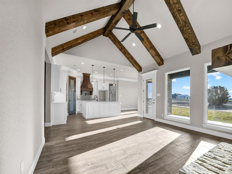 Unfurnished living room with dark wood-type flooring, ceiling fan, beamed ceiling, sink, and high vaulted ceiling