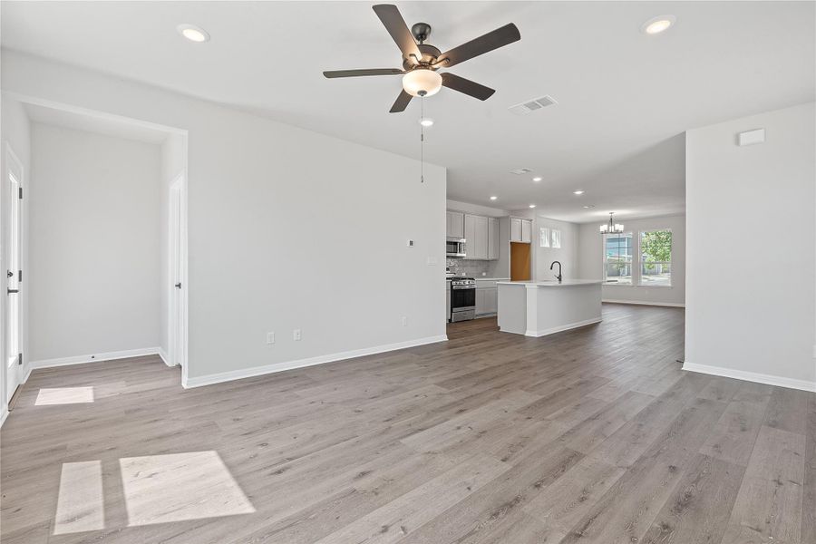 Unfurnished living room featuring a ceiling fan, recessed lighting, light wood-type flooring, and a chandelier