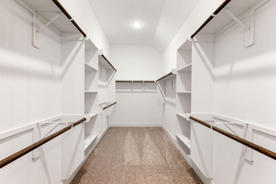 Check out this huge walk-in primary closet with built in shelving and recess lighting.