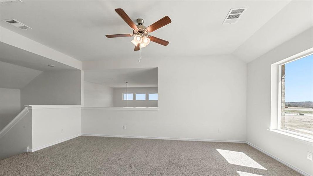 Carpeted empty room with vaulted ceiling and a ceiling fan