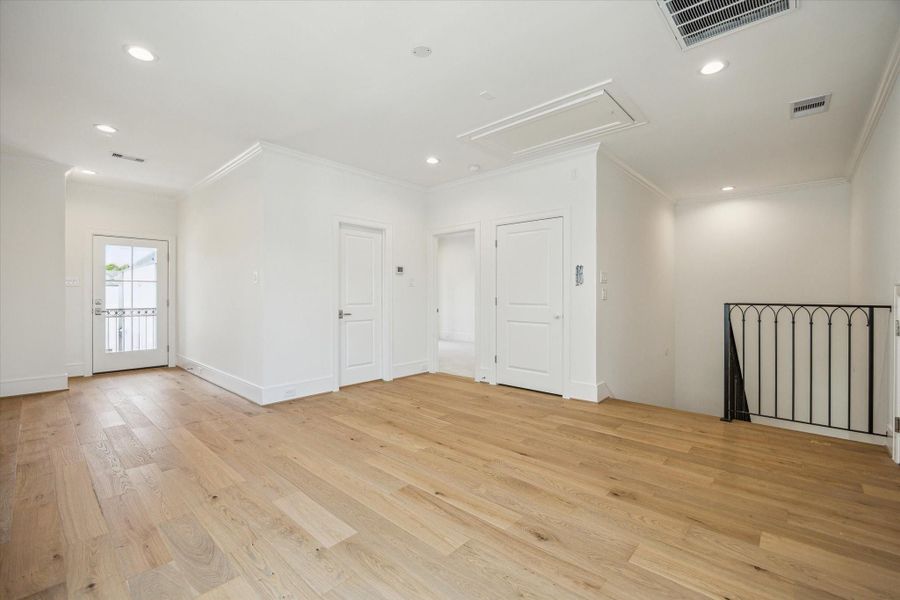 Third-floor game room, access to balcony through glass door on left, secondary bedroom through middle door on right.